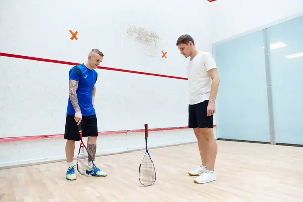 Tricks. Two men standing on squash court and playing. Leisure activity, fun and sportive time. Concept of sport, hobby, healthy and active lifestyle, game, gym, ad