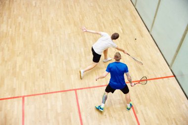 Squash kortunda squash oynayan iki genç adam, arkadaşlar, sporcular. Rekabet. Dinamik. Spor anlayışı, hobi, sağlıklı ve aktif yaşam tarzı, oyun, spor salonu, reklam