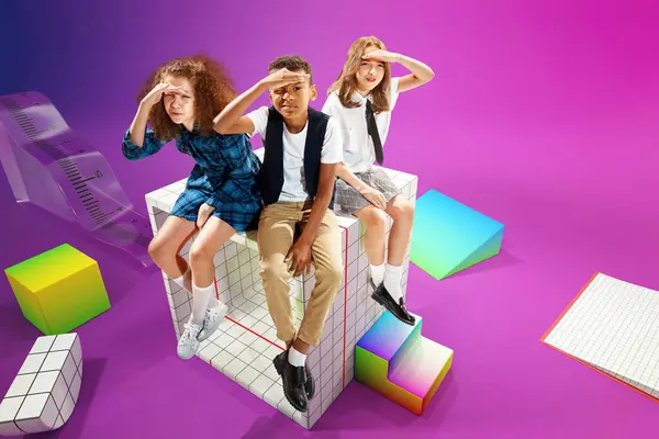 Looking for new knowledges. Children, school boy and girls sitting on 3D school supplies over colorful background. Concept of childhood, education, school, lifestyle, knowledge. Colorful collage.