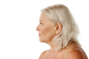 Yüzü buruşuk, omuzları beyaz stüdyo geçmişine bakan yaşlı bir kadının yan görüntüsü. Doğal güzellik kavramı, yaşlanma süreci, yaşlı güzellik, kozmetoloji, cilt bakımı