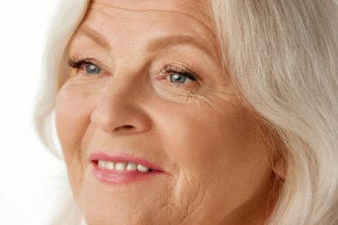 Beyaz stüdyo arka planında güzel buruşuk yüzlü, son sınıf çekici bir kadının yakın plan görüntüsü. Doğal güzellik kavramı, yaşlanma süreci, yaşlı güzellik, kozmetoloji, cilt bakımı