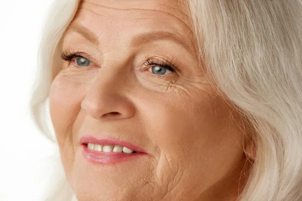 Beyaz stüdyo arka planında güzel buruşuk yüzlü, son sınıf çekici bir kadının yakın plan görüntüsü. Doğal güzellik kavramı, yaşlanma süreci, yaşlı güzellik, kozmetoloji, cilt bakımı