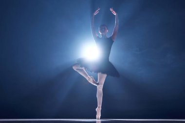 Hareketlerde zarafet ve zarafet. Mavi arka planda spot ışıklarıyla dans eden güzel bir balerin. Klasik dans, sanat ve zarafet kavramı, güzellik, koreografi, ilham