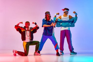 Kaslarını gösteriyor. Genç erkekler, renkli spor kıyafetleri içindeki canavarlar neon ışıkta değişen pembe arka plana karşı antrenman yapıyorlar. Sportif ve aktif yaşam tarzı, mizah, eski tarz kavramı. Ad