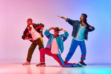 Tarz sahibi, yakışıklı, üç adam eski tarz spor giyim tarzında, neon lambalı, değişken pembe arka plana karşı. Sportif ve aktif yaşam tarzı, mizah, eski tarz kavramı. Ad