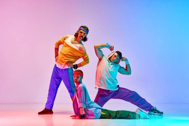 Kaslarını gösteriyor. Genç erkekler, renkli spor kıyafetleri içindeki canavarlar neon ışıkta değişen pembe arka plana karşı antrenman yapıyorlar. Sportif ve aktif yaşam tarzı, mizah, eski tarz kavramı. Ad