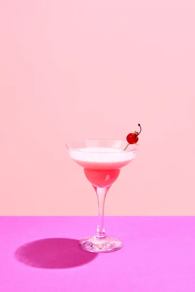 Pink lady, Clover club cocktail with cherry decorations standing against pink background. Sweet, fresh taste. Concept of alcohol drinks, party, holidays, bar, mix. Poster. Copy space for ad
