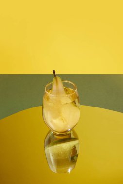 Lezzetli, armut tadında tatlı bir kokteyl. Sarı arka planda, aynanın üzerinde duruyor. Yaz tadı. İçki, parti, tatil, bar, karışım kavramı. Poster. İlan için alanı kopyala