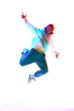 30 'lu yaşlarda spor kıyafetleri giyen ve dans eden bir adam beyaz stüdyo arka planında neon ışıklarıyla izole edilmiş. Çağdaş dans kavramı, sokak tarzı, moda, hobi, gençlik. Ad