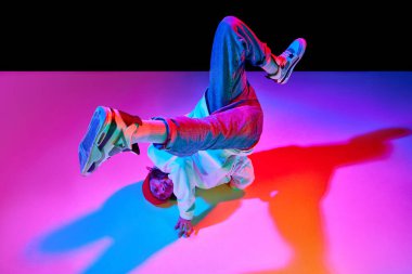 30 'larında hareketli bir adamın dinamik görüntüsü, neon ışıklarıyla siyah stüdyo arka planında izole edilmiş dans break dansı. Çağdaş dans kavramı, sokak tarzı, moda, hobi, gençlik. Ad