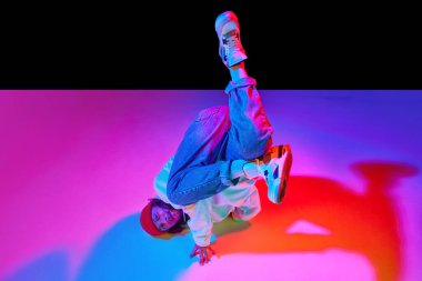 30 'larında hareketli bir adamın dinamik görüntüsü, neon ışıklarıyla siyah stüdyo arka planında izole edilmiş dans break dansı. Çağdaş dans kavramı, sokak tarzı, moda, hobi, gençlik. Ad