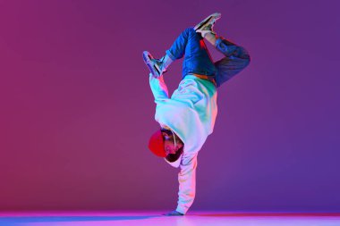 Hareketli şık spor kıyafetleri içindeki adam, dans eden break dans, neon ışıklarıyla izole edilmiş gradyan stüdyo arkaplanı. Çağdaş dans kavramı, sokak tarzı, moda, hobi, gençlik. Ad