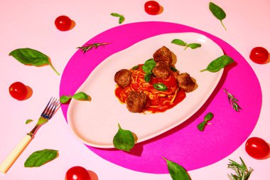 Restoran servisi. Lezzetli İtalyan yemeği, köfteli makarna ve pembe arka planda fesleğen yaprakları. Spagetti ve domates sosu. İtalyan yemeği, yemek, tat, menü kavramı. Pop sanat. Poster, reklam