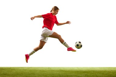 Atletik genç bir kadın, maç sırasında hareket halinde olan bir futbolcu, beyaz arka planda izole bir şekilde çim alanda topa vuruyor. Spor, rekabet, eylem, başarı, motivasyon kavramı. İlan için alanı kopyala