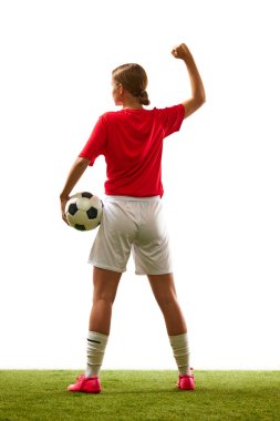 Genç bir kadın, üniformalı bir futbolcu, beyaz arka planda topu çimlerin üzerinde duruyor. Spor, rekabet, aksiyon, başarı, kazanma kavramı. İlan için alanı kopyala