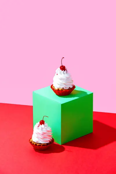 Sweet cakes with cherry decoration on green cube over red pink background. Concept of food, desserts, birthday celebration, party, bakery. Pop art style. Copy space for ad. Poster