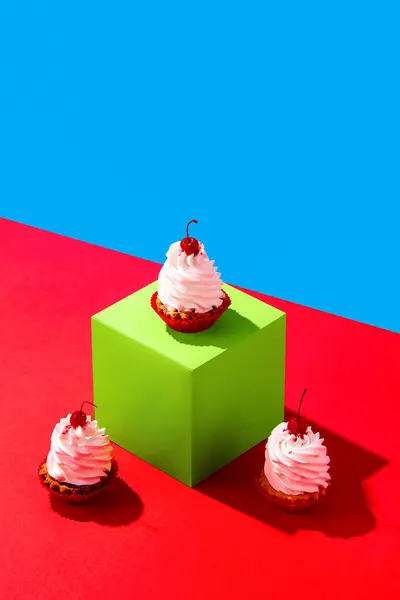 Sweet cakes with cherry decoration on green cube over red blue background. Concept of food, desserts, birthday celebration, party, bakery. Pop art style. Copy space for ad. Poster