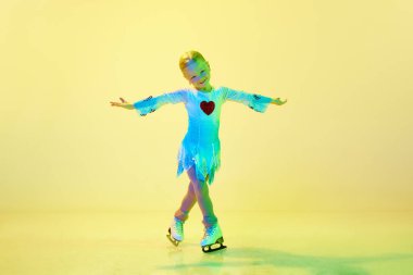 Sanatsal, yetenekli küçük kız, çocuk, kostüm dansındaki sevimli çocuk, neonlu sarı arka planda artistik patinaj eğitimi almış. Çocukluk kavramı, artistik patinaj sporu, hobi, okul, eğitim
