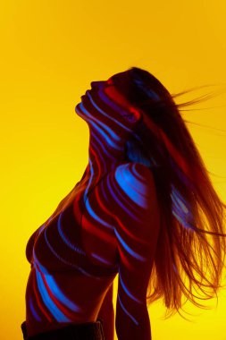 Şefkat ve duygusallık. Üzerinde renkli neon çizgiler olan sarı arka plana karşı zarif genç bir kadın. Modern sanat, güzellik, tarz, fütürizm ve siber punk, yaratıcılık kavramı