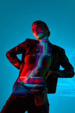 İnce, rahatlatıcı bir vücudu olan çekici genç bir kadın mavi arka planda poz veriyor ve vücudunda neon ışıkları yansıyor. Modern sanat, güzellik, tarz, fütürizm ve siber punk, yaratıcılık kavramı