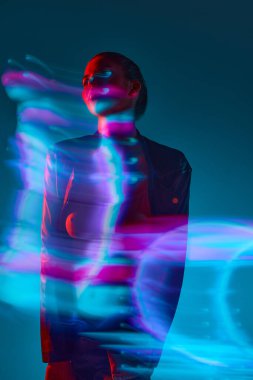 Mavi arka planda karışık neon ışık efektiyle duran genç bir kadının silueti. Hologram. Modern sanat, güzellik, tarz, fütürizm ve siber punk, yaratıcılık kavramı