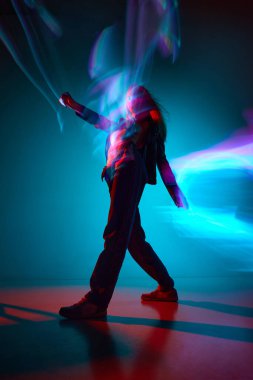 Gerçeküstü yürüyüş. Mavi arka planda, neon ışıkları yansıması olan genç bir kızın alt görüntüsü. Modern sanat, güzellik, tarz, fütürizm ve siber punk, yaratıcılık kavramı