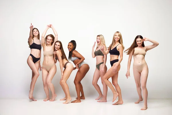 Body positive. Attractive different young women of diverse skin color, age and body shapes in underwear against white studio background. Concept of multi-ethnic beauty, body acceptance, self-care