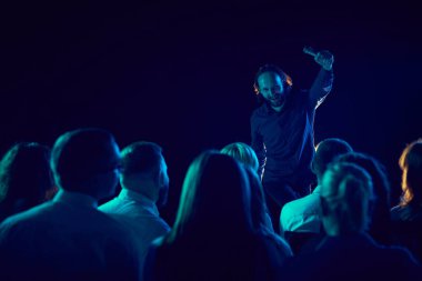 Genç adam, ayağa kalk ve sahnede dur, gül, neşeli bir şekilde seyircilere komik hikayeler ve şakalar anlat. Eğlence kavramı, eğlence ve neşe, konser, performans, gösteri