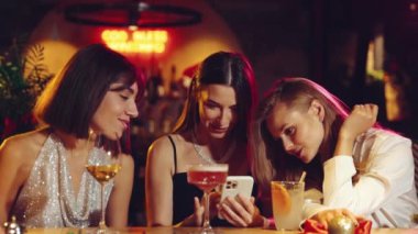 Güzel kadınlar barda buluşuyor, sosyal medyada kayıyor, tartışıyor, gülüyor, kokteyl içiyor. Noel partisi kavramı, kış tatili, kutlama, arkadaşlık, eğlence, rahatlama