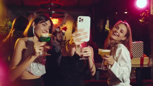 エレガントで 幸せで 笑顔の若い女性がバーで踊り カクテルを飲んで 電話でビデオを録画しています クリスマスパーティー 冬休み お祝い 楽しみ リラクゼーションのコンセプト — ストック動画