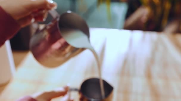 女性のバリスタワーカーがミルクを投手に注いでいる カプチーノの準備 ラテコーヒードリンク テーブルの上の日光 コーヒー産業 喫茶店 カフェテリア ビジネスの概念 — ストック動画