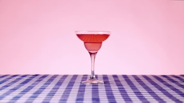 Glas Mit Süßem Manhattan Cocktail Auf Karierter Tischdecke Über Rosa — Stockvideo