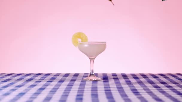 甜而酸的玛格丽塔鸡尾酒放在粉色背景的格子桌布上 用迷迭香枝条装饰酒水的酒保 鸡尾酒 酒精饮料 流行艺术风格的概念 — 图库视频影像