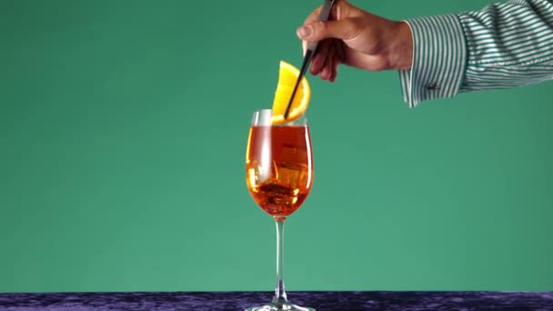 调酒师制作受欢迎的饮料 Aperol Spritz鸡尾酒 装饰橙色片和橄榄绿色背景 鸡尾酒 酒精饮料 流行艺术风格的概念 — 图库视频影像