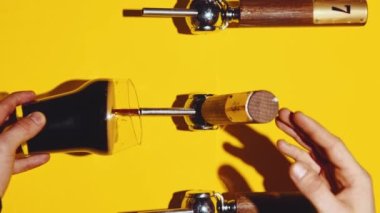 Barmen yavaşça sarı arka planda bardağa koyu bira dolduruyor. Baloncuklar. Bira barı, degukasyon. Bira fabrikası kavramı, tat, bar, degulasyon, festival, içki dokusu. Dikey yerleşim