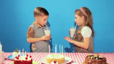 Mutlu, neşeli güzel çocuklar, erkek ve kız doğum gününü kutluyorlar, mavi arka planda milkshake içiyorlar. Çocukluk kavramı, doğum günü kutlaması, aile, eğlence, yemek