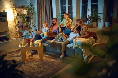 Aile, anne, baba ve küçük çocuklar, evdeki kanepede oturan ve televizyon izleyen çocuklar. Sıkıldım. Aile kavramı, boş zaman, rahatlama, çocukluk ve ebeveynlik