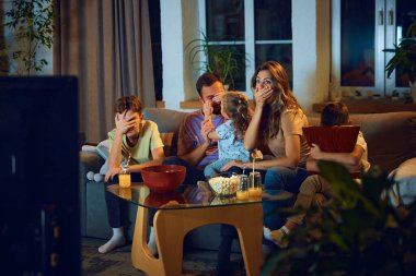 Akşamları evde televizyon izleyen bir aile. Çocuklu aileler kanepede oturur, korku filmi izler, gözleri korku içinde kapatırlar. Aile kavramı, boş zaman, rahatlama, çocukluk ve ebeveynlik