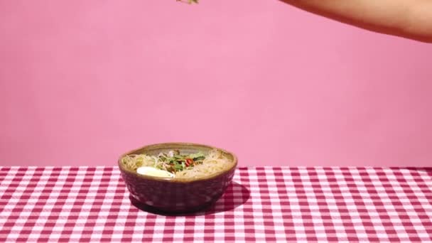 女性的手把新鲜的香菜放在盘子里 配上米粉和粉红色背景的格子桌布 亚洲食物 流行艺术风格 配料的概念 — 图库视频影像