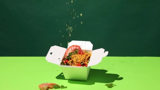 在绿色背景的纸盒中 西兰油与虾仁和烤蔬菜一起倒入美味的乌冬面中 亚洲食物 流行艺术风格 配料的概念 — 图库视频影像