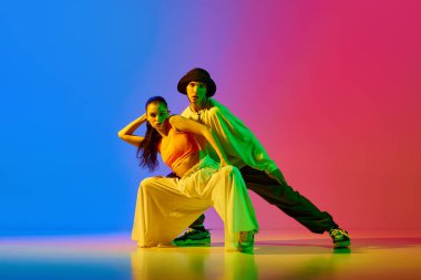 Sanatçı, yetenekli, etkileyici genç kadın ve erkek, dansçılar neon ışıkta mavi arka planda hip hop yapıyorlar. Hobi, eylem, sokak tarzı, modern dans, gençlik, moda kavramı