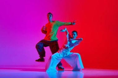 Genç yetenekli insanlar, sokak dansı yapan kadın ve erkek, neon ışıkta pembe arka planda hip hop. Hobi, eylem, sokak tarzı, modern dans, gençlik, moda kavramı