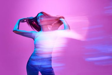 Açık mor arka planda neon ışıklarda poz veren zarif genç bir kadının portresi. Siluet. Işıkların yansıması. Sanat anlayışı, modern tarz, siber punk, fütürizm ve yaratıcılık