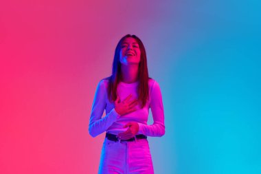 30 'lu yaşlardaki genç kadınlar gündelik giysiler giyip neon ışıklarıyla gradyan pembe stüdyonun arka planına gülüyorlar. İnsan duyguları kavramı, yaşam tarzı, gençlik kültürü, yüz ifadesi