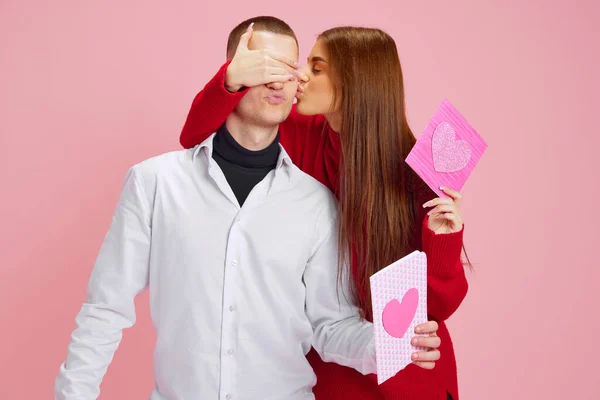 亲一下年轻姑娘捂住男朋友的眼睛 带着小礼物送给他 明信片上有粉红色的背景 爱的概念 情人节 生活方式 — 图库照片