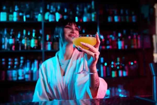 Focus on delicious sweet and sour cocktail. Beautiful young girl, bartender serving cocktail. Neon colored bar. Concept of occupation, nightlife, bar, party, alcohol drink, mixologist