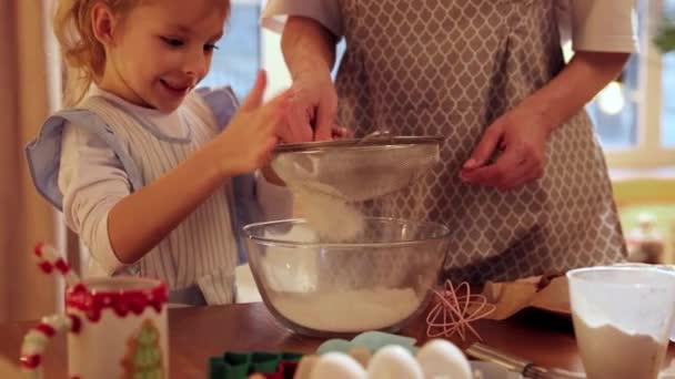 妈妈和小女儿在厨房里一起做饭 小女孩做面团 和妈妈一起筛面 寒假饼干日 家庭的概念 — 图库视频影像