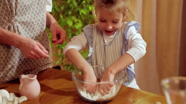 小女孩 穿着围裙的孩子 和妈妈一起站在厨房里教她烘焙饼干 孩子在赚钱饼干日 家庭的概念 — 图库视频影像