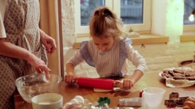 Mutlu aile zamanları. Genç bir kadın, annesi küçük bir kızla yemek pişiriyor, kızı modern bir evde. Kruvasan ve kurabiye pişiriyorum. Kurabiye günü kavramı, annelik, çocukluk, tatiller, aile