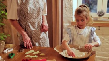 Anne ve küçük kızı evde yemek pişiriyor, Noel kurabiyeleri pişiriyor. Evde sıcak bir akşam. Pişirmeyi öğreniyorum. Kurabiye günü kavramı, annelik, çocukluk, tatiller, aile